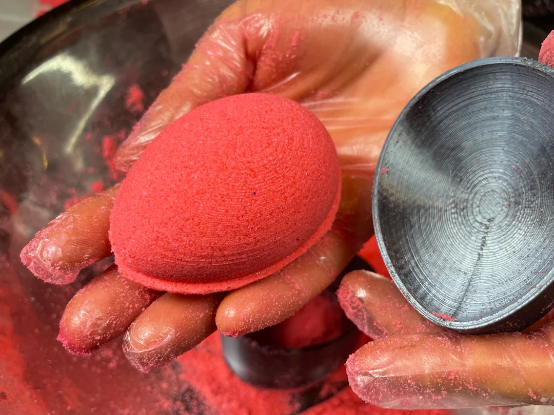 A maker releasing a red bath bomb from its mold